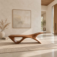 Long low wooden bench with a triangular open leg and a swept tapered end in a bright open plan entryway