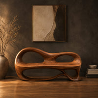 Bench with a sculpted back that has two oval openings in a dark studio against a charcoal plaster wall