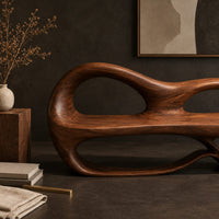 Corner detail of bench with a sculpted back that has two oval openings beside wood, brass and linen samples