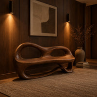 Bench with a sculpted back that has two oval openings in an evening entryway with walnut wall paneling