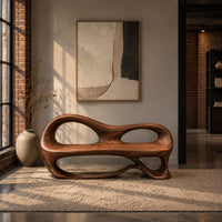 Bench with a sculpted back that has two oval openings in an industrial loft entryway with exposed brick
