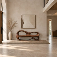 Bench with a sculpted back that has two oval openings in a bright open plan entryway