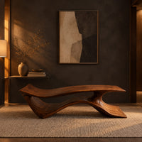 Long low bench with a wave shaped plank seat on a swept base in a dark entryway at golden hour
