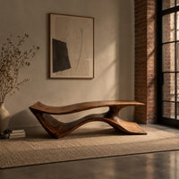 Long low bench with a wave shaped plank seat on a swept base in an industrial loft entryway with exposed brick