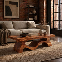 Low rectangular coffee table with a thick top and a wave ribbon base in an industrial loft living room with exposed brick