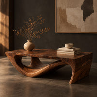 Corner detail of rectangular coffee table with a thick top over a swooping open loop base beside wood, brass and linen samples