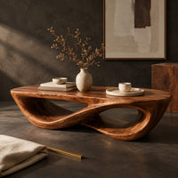 Corner detail of coffee table with a twisting figure eight base and a thick oval top beside wood, brass and linen samples