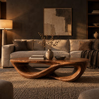 Coffee table with a twisting figure eight base and a thick oval top in a dark living room at golden hour