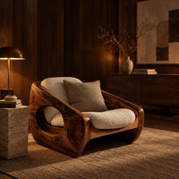 Sculpted wooden lounge chair with a circular side opening and cream cushions in an evening living room with walnut wall paneling