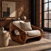 Sculpted wooden lounge chair with a circular side opening and cream cushions in an industrial loft living room with exposed brick