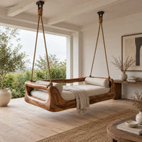 Hanging daybed swing with a sculpted wood frame and a cushioned seat in a Scandinavian porch with white walls