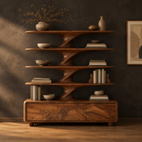 Bookshelf with sculpted flared tiers on a low base with three front panels in a dark studio against a charcoal plaster wall
