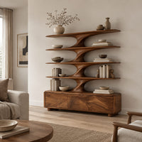 Bookshelf with sculpted flared tiers on a low base with three front panels in a Scandinavian living room with white walls