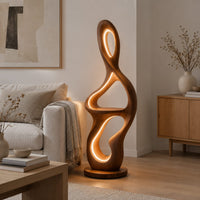 Sculpted floor lamp with glowing oval cutouts and a mid level shelf in a Scandinavian living room with white walls