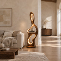 Sculpted floor lamp with glowing oval cutouts and a mid level shelf in a bright open plan living room