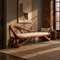 Sculpted wooden bench with open branching sides and a padded seat in an industrial loft entryway with exposed brick