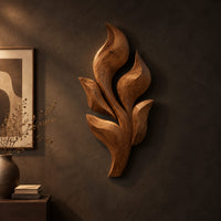Sculpted wooden leaf cluster wall art in layered shapes on a dark charcoal plaster wall