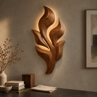 Detail of sculpted wooden leaf cluster wall art in layered shapes beside wood, brass and linen samples