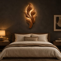 Sculpted wooden leaf cluster wall art in layered shapes above a bed in a dusk lit bedroom