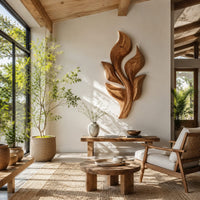 Sculpted wooden leaf cluster wall art in layered shapes in a bright sunroom with green plants