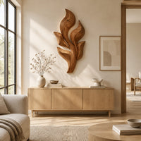 Sculpted wooden leaf cluster wall art in layered shapes above a light oak sideboard in daylight
