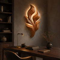 Sculpted wooden leaf cluster wall art in layered shapes above a desk in a dark study corner