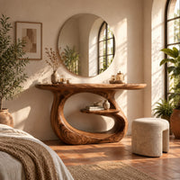 Oval top makeup vanity on a looping pedestal base with a small inner shelf in a bright bedroom with arched windows and plants