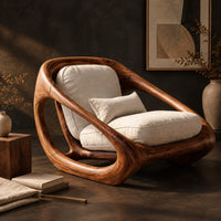 Corner detail of sculpted lounge chair with a thick looping wood frame and open side cutouts beside wood, brass and linen samples