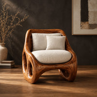Lounge chair with circular side cutouts and a high back with cream cushions in a dark studio against a charcoal plaster wall