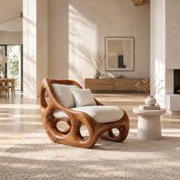 Lounge chair with circular side cutouts and a high back with cream cushions in a bright open plan living room