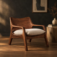 Lounge chair with looped arms and a swept wooden back in a dark studio against a charcoal plaster wall
