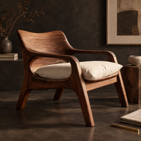 Corner detail of lounge chair with looped arms and a swept wooden back beside wood, brass and linen samples