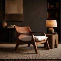Lounge chair with looped arms and a swept wooden back in a dark living room at golden hour