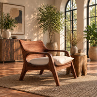 Lounge chair with looped arms and a swept wooden back in a bright living room with arched windows and plants