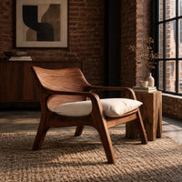 Lounge chair with looped arms and a swept wooden back in an industrial loft living room with exposed brick