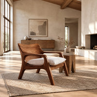 Lounge chair with looped arms and a swept wooden back in a bright open plan living room