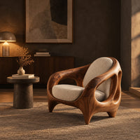 Sculpted lounge chair with an open cutout wood frame and cream cushions in a dark living room at golden hour