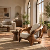 Sculpted lounge chair with an open cutout wood frame and cream cushions in a bright living room with arched windows and plants