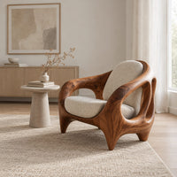 Sculpted lounge chair with an open cutout wood frame and cream cushions in a Scandinavian living room with white walls