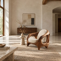 Sculpted lounge chair with an open cutout wood frame and cream cushions in a bright open plan living room