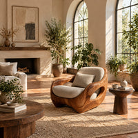 Sculpted lounge chair with open oval side cutouts and a cushioned seat in a bright living room with arched windows and plants