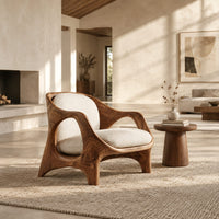 Sculpted lounge chair with open side cutouts and cream cushions in a bright open plan living room