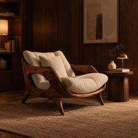 Lounge chair with a sculpted wooden frame and thick cream cushions in an evening living room with walnut wall paneling