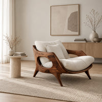 Lounge chair with a sculpted wooden frame and thick cream cushions in a Scandinavian living room with white walls
