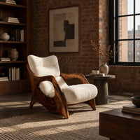 Sculpted wooden lounge chair with open side loops and cream cushions in an industrial loft living room with exposed brick