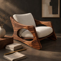 Corner detail of sculptural lounge chair with oval side cutouts and a cushioned seat beside wood, brass and linen samples