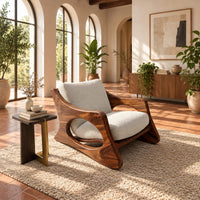 Sculptural lounge chair with oval side cutouts and a cushioned seat in a bright living room with arched windows and plants