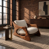 Sculptural lounge chair with oval side cutouts and a cushioned seat in an industrial loft living room with exposed brick