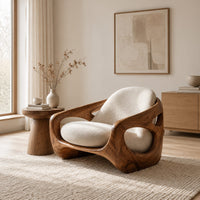 Sculpted lounge chair with oval side cutouts and cream seat cushions in a Scandinavian living room with white walls