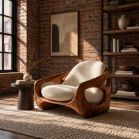 Sculpted lounge chair with oval side cutouts and cream seat cushions in an industrial loft living room with exposed brick